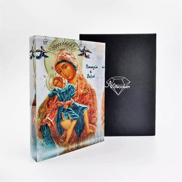 A hand-painted icon of Our Lady of the Right, depicted in vibrant colors with a 3D effect, placed next to its black cover with a diamond-shaped logo on it.