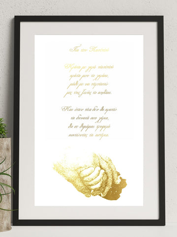 A framed print with text in Greek, possibly a personalized message, displayed on a wall. The frame appears to be black, and there is a gold foil detail on the text.