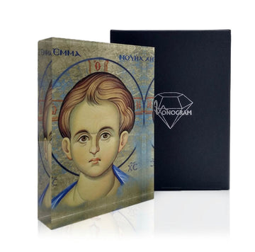 An icon depicting the face of Jesus Christ, with a 3D effect, alongside a black book with a diamond-shaped logo on the cover, all part of the Monogram Atelier collection.