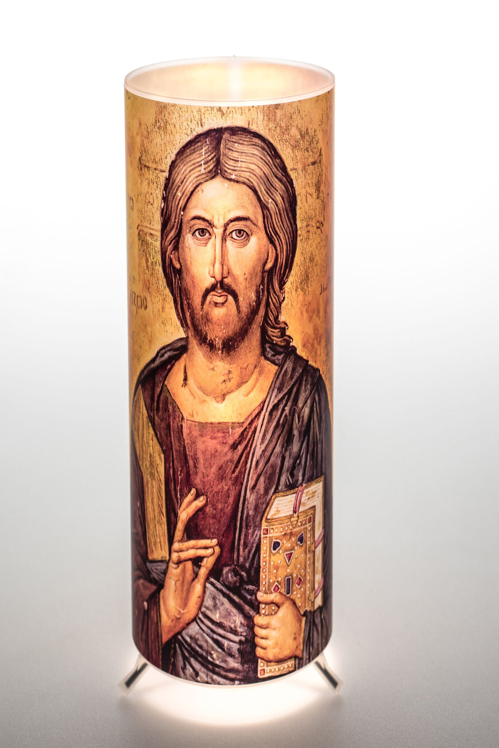 A tall cylindrical candle lantern with a Greek Orthodox icon on the side, featuring a picture of Jesus Christ, and a lampshade on top.