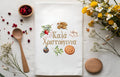 Decorative tea towel with Greek festive design and text, surrounded by Greek Sweets