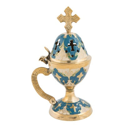 A colored incense burner with a decorative design, featuring a cross on the top and a handle on the side, against a white background.