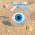 Clear hand blow glassornament with blue and white evil eye design mati on sand