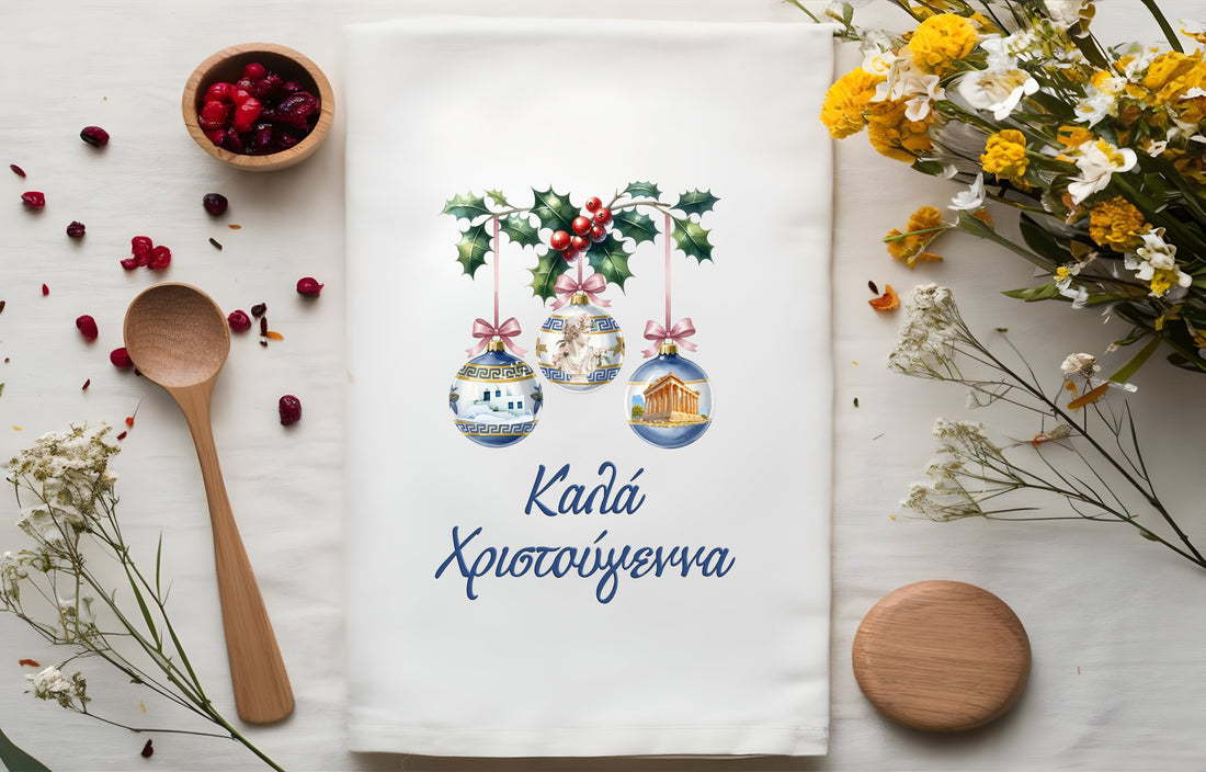 GreeknTea towel with pomegranate design, wooden spoon, and flowers on a white surface
