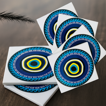 Set of six decorative coasters with evil eye circular patterns on a brown surface.