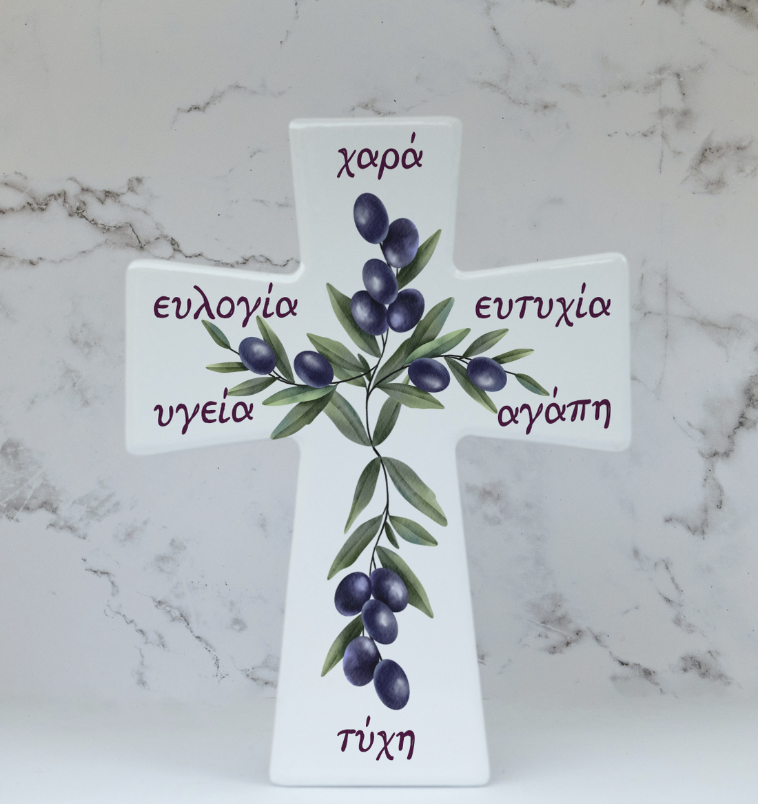 A ceramic cross with a floral design and Greek text, standing on a marble surface.