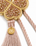 Close-up of four leaf clover gouri showing sparkling rhinestone detail, tassel and small 26 gold tag.