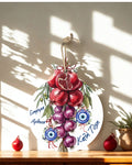 Decorative wall art with pomegranates and grapes on a wooden surface with sunlight casting shadows.