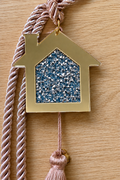 Gold acrylic house gouri lucky charm with blue and silver rhinestones and white cord