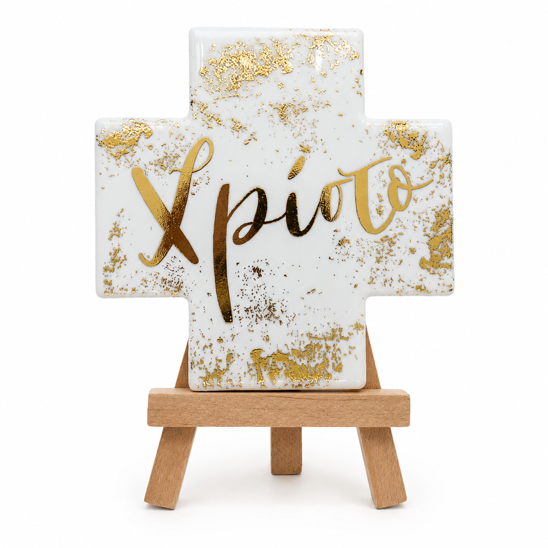 White ceramic Greek Orthodox name cross with silver detailing displayed on a wooden stand in a warm neutral prayer corner setting