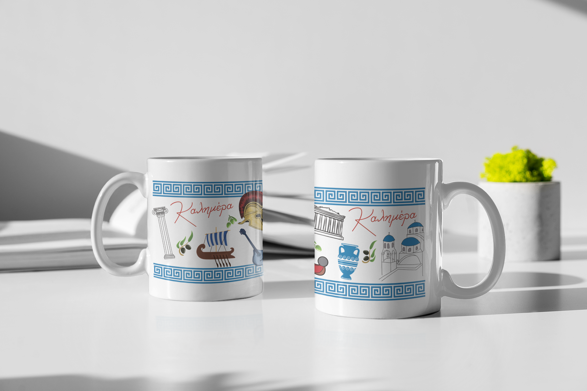 White ceramic mug with the Greek word ‘Καλημέρα’ (Kalimera) meaning ‘Good Morning’, featuring traditional Greek motifs including olive branches, ancient columns, Santorini domes, pottery, and blue meander border.