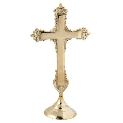 An ornate brass cross with a gold or silver finish, featuring intricate details and a prominent central crucifix.