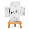 White ceramic Greek Orthodox cross with silver name lettering and silver foil detail on a wooden stand
