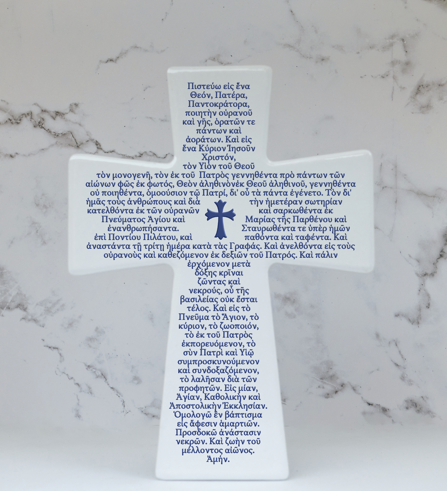 A ceramic cross with a glossy finish, featuring the Greek text for 'The Creed of Faith' inscribed on it, displayed against a marble background.