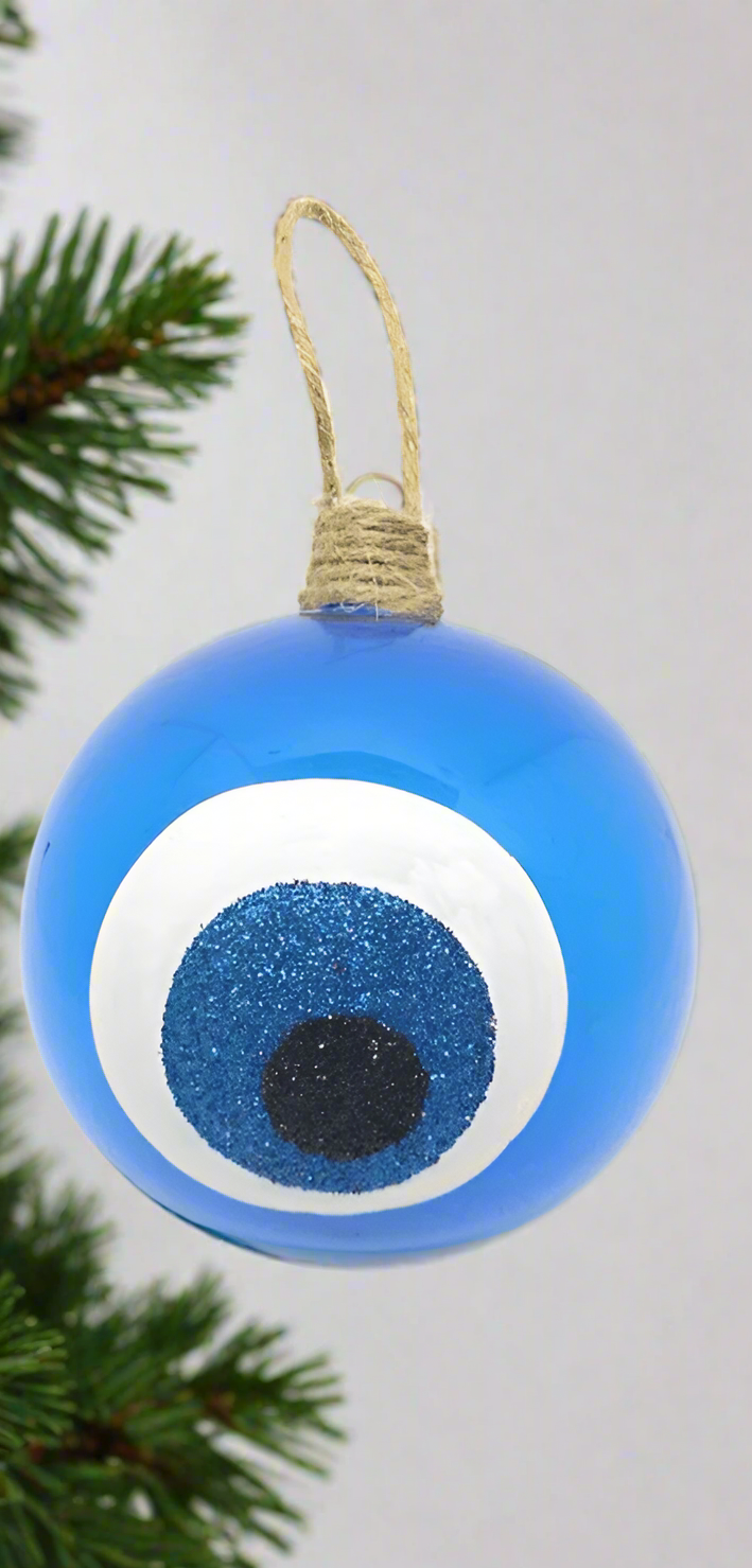 A round blue glass bauble with a white and black patterned evil eye design, with a jute hanging ribbon at the top.