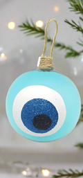 A turquoise round hand blown glass bauble with blue and white colors and a glittery finish, featuring an evil eye design, hanging from a twine.