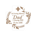 A ceramic memorial cross with a white cross design, bronze accents, and floral patterns around the border. The cross includes a personalized inscription in memory of a father, with dates of birth and death.
