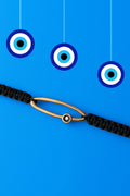 Black cord macrame bracelet with evil eye on a blue background with hanging evil eye charms.