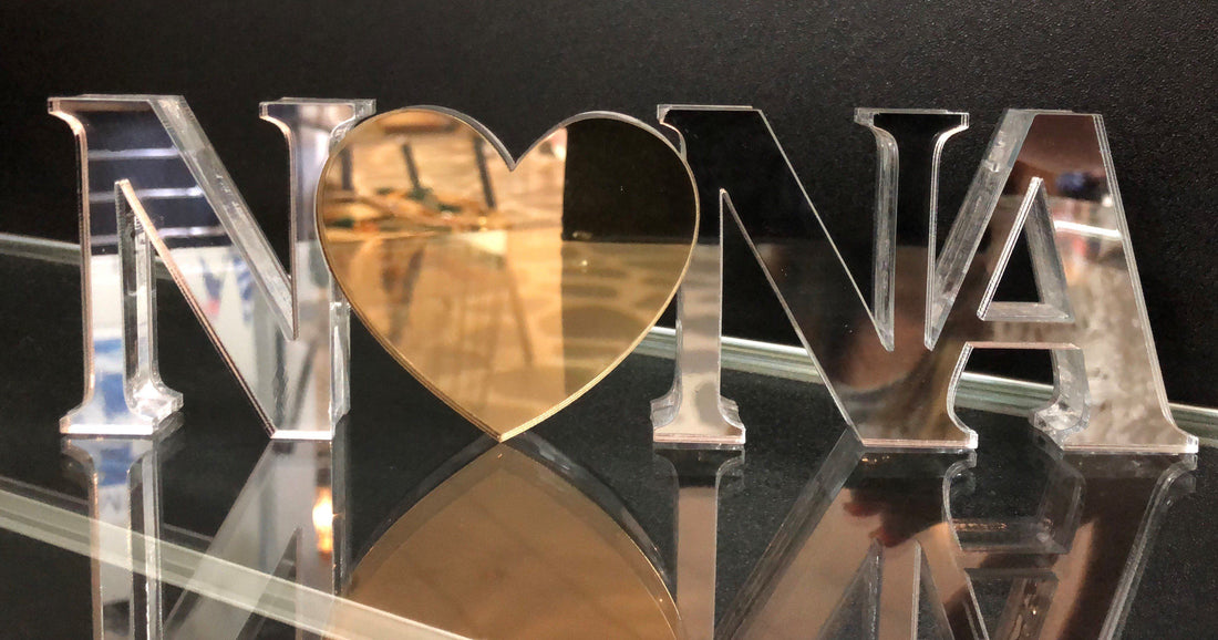 A personalized acrylic plaque with the name 'Nona' cut out in the shape of a heart, with a mirror like finish.