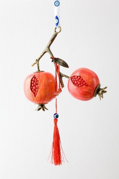 Hanging Greek pomegranate gouri lucky charm with red tassel and branch detail.