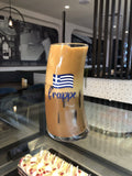 Original Wave Frappe Glass with Greek flag design, filled with iced Greek frappe at a café