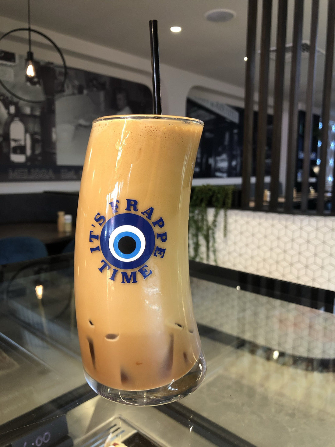 Original Wave Frappe Glass with Greek flag design, filled with iced Greek frappe at a café