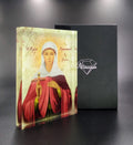 Orthodox plexiglass icon of Saint Anastasia Pharmakolytria displayed with branded Monogram Atelier gift box. Handmade Greek icon with healing cross and light textured backdrop.
